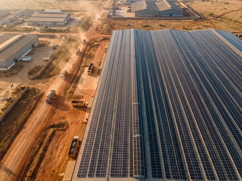 Rows of solar panels covering a large warehouse roof in an industrial area