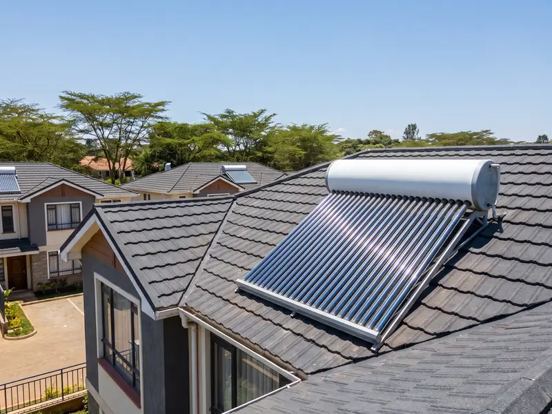 An evacuated-tube solar water heater on the tiled roof of a modern maisonette